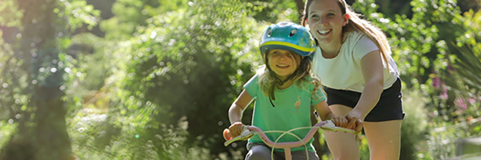 mom teaching her daughter to ride a bike outdoors