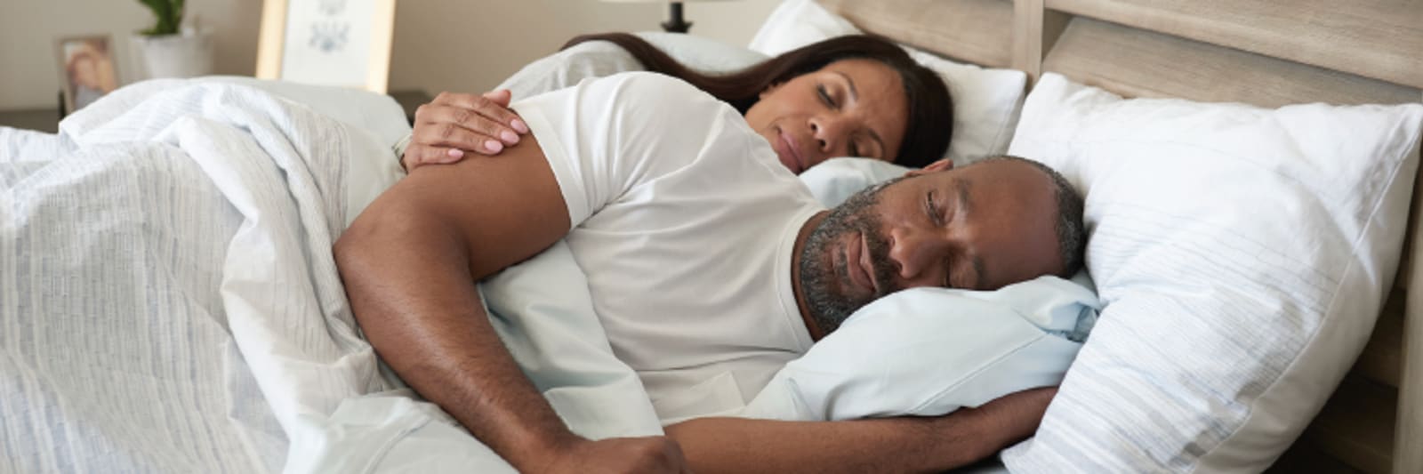 a black man and woman sleep peacefully in a bed together