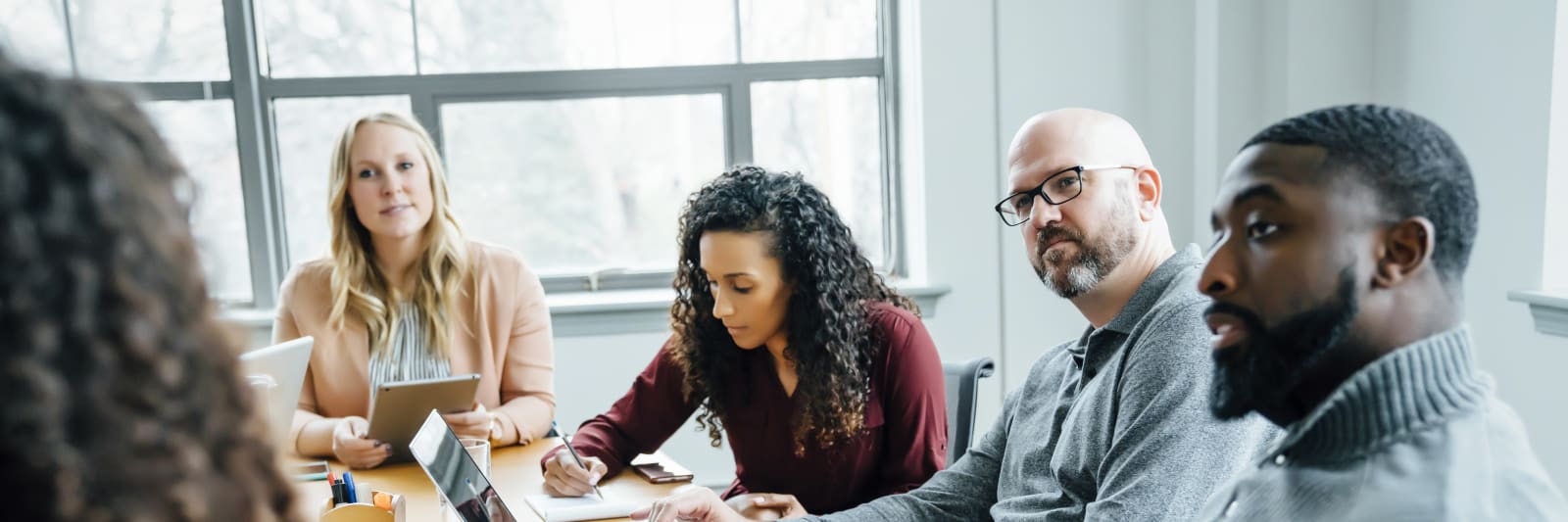 A diverse group of five people interacting during a boardroom meeting.