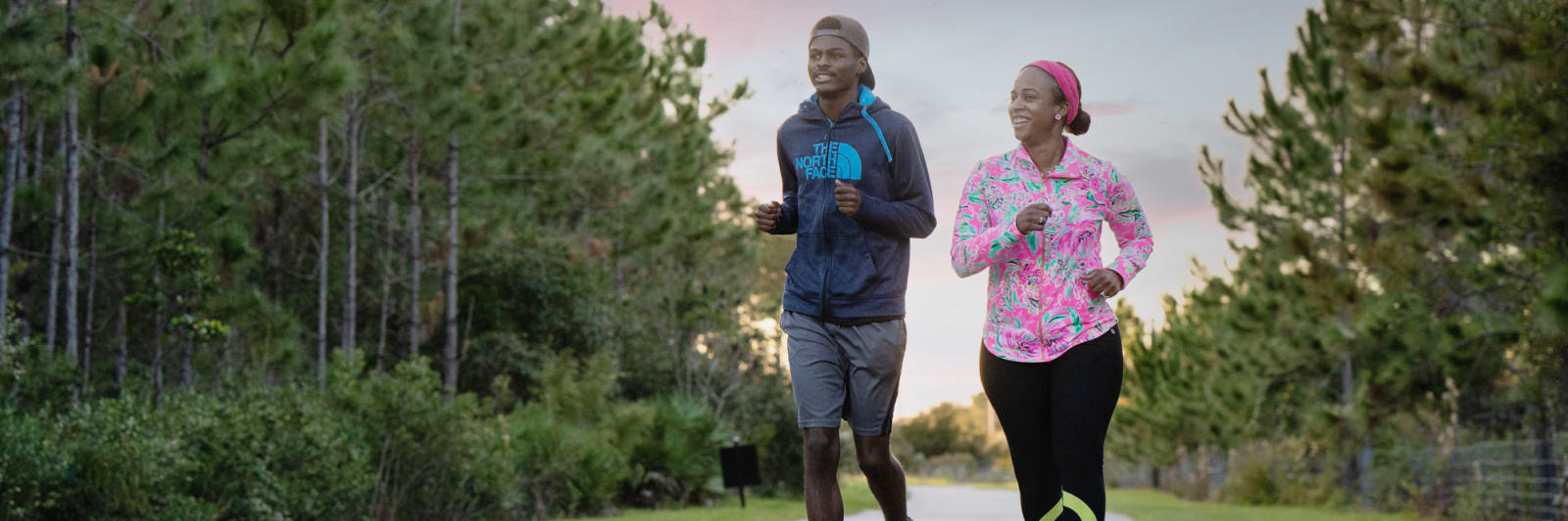 mother and son running together on a wooded trail outside