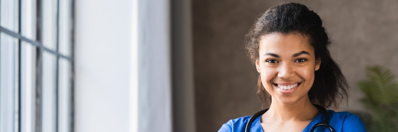 Portrait of african-american female doctor with stethoscope by a window.