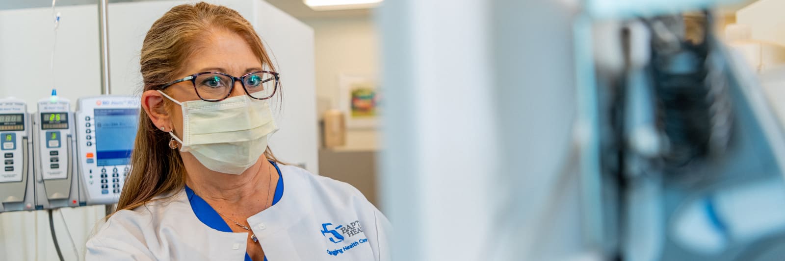 close up of female practitioner looking at a screen with medical equipment behind her