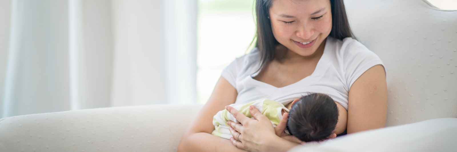 smiling mother breastfeeding her newborn baby