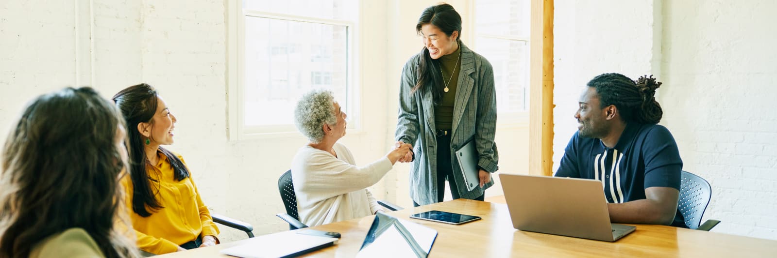 Smiling businesswoman shaking hands with team in conference room
