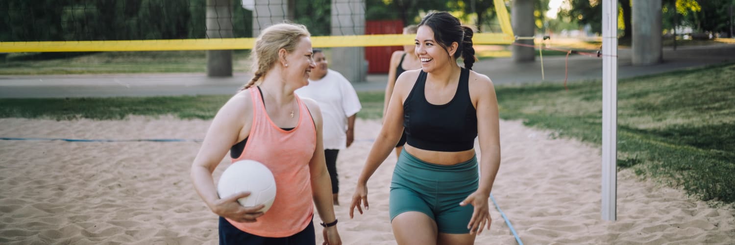 a group of female friends talking on a volleyball court