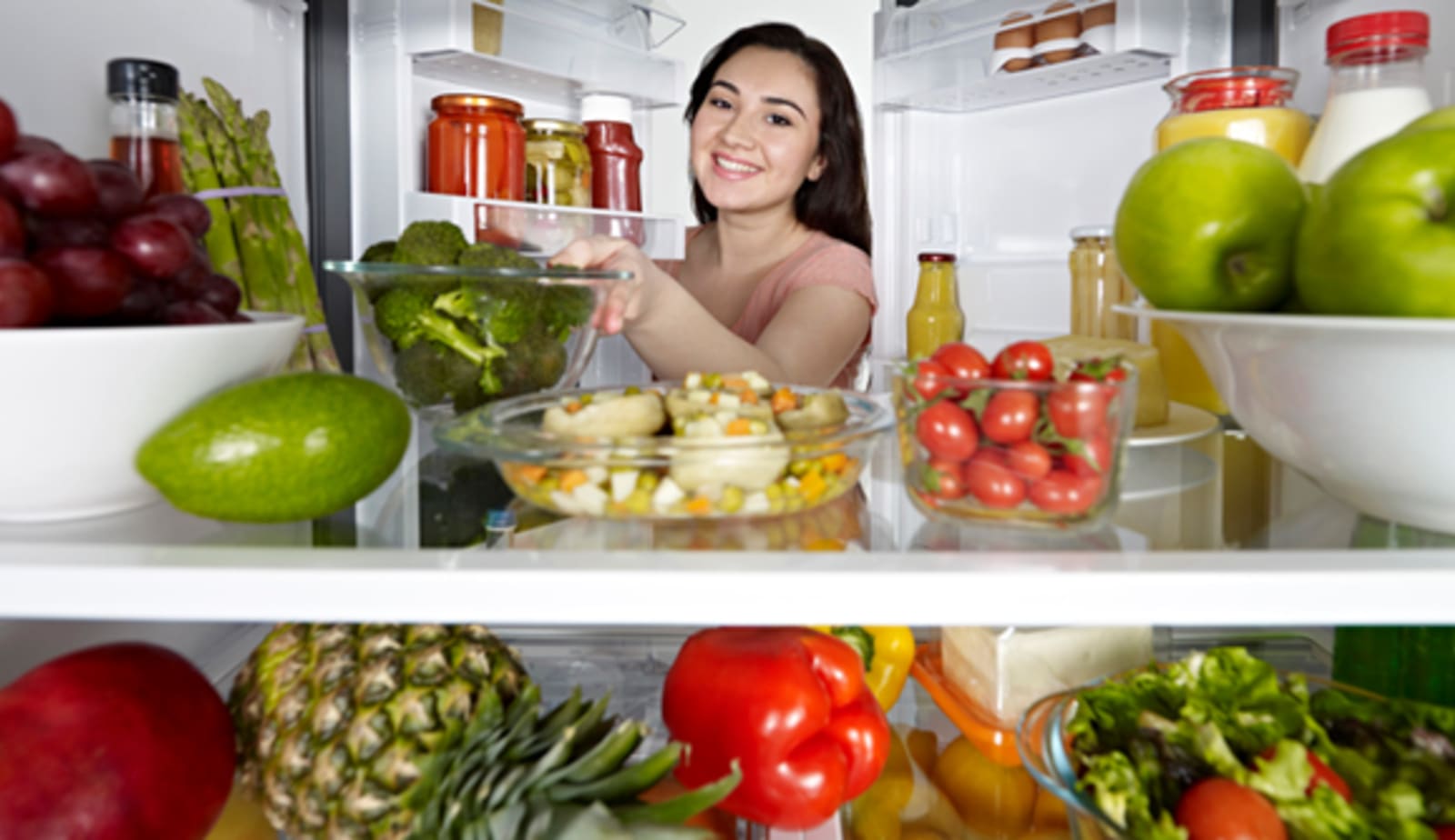 woman looking at healthy foods in her refrigerator