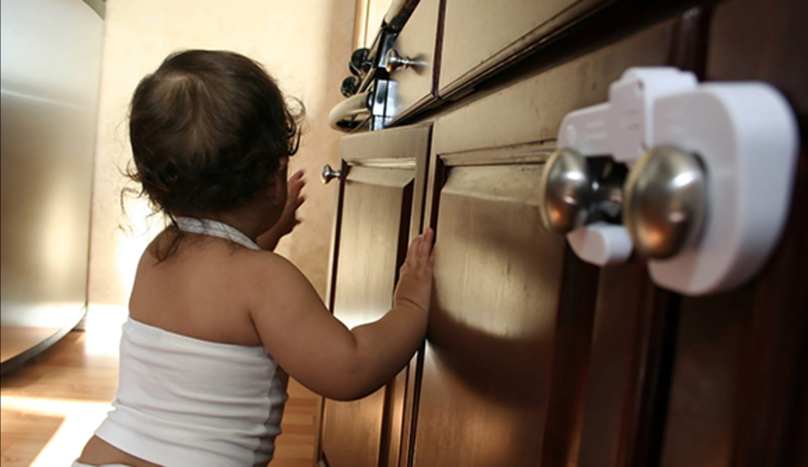 A baby investigates cabinets with baby locks.