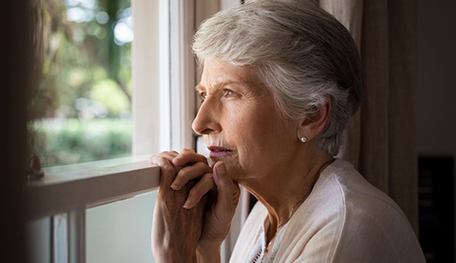 senior woman gazing out the window forlornly