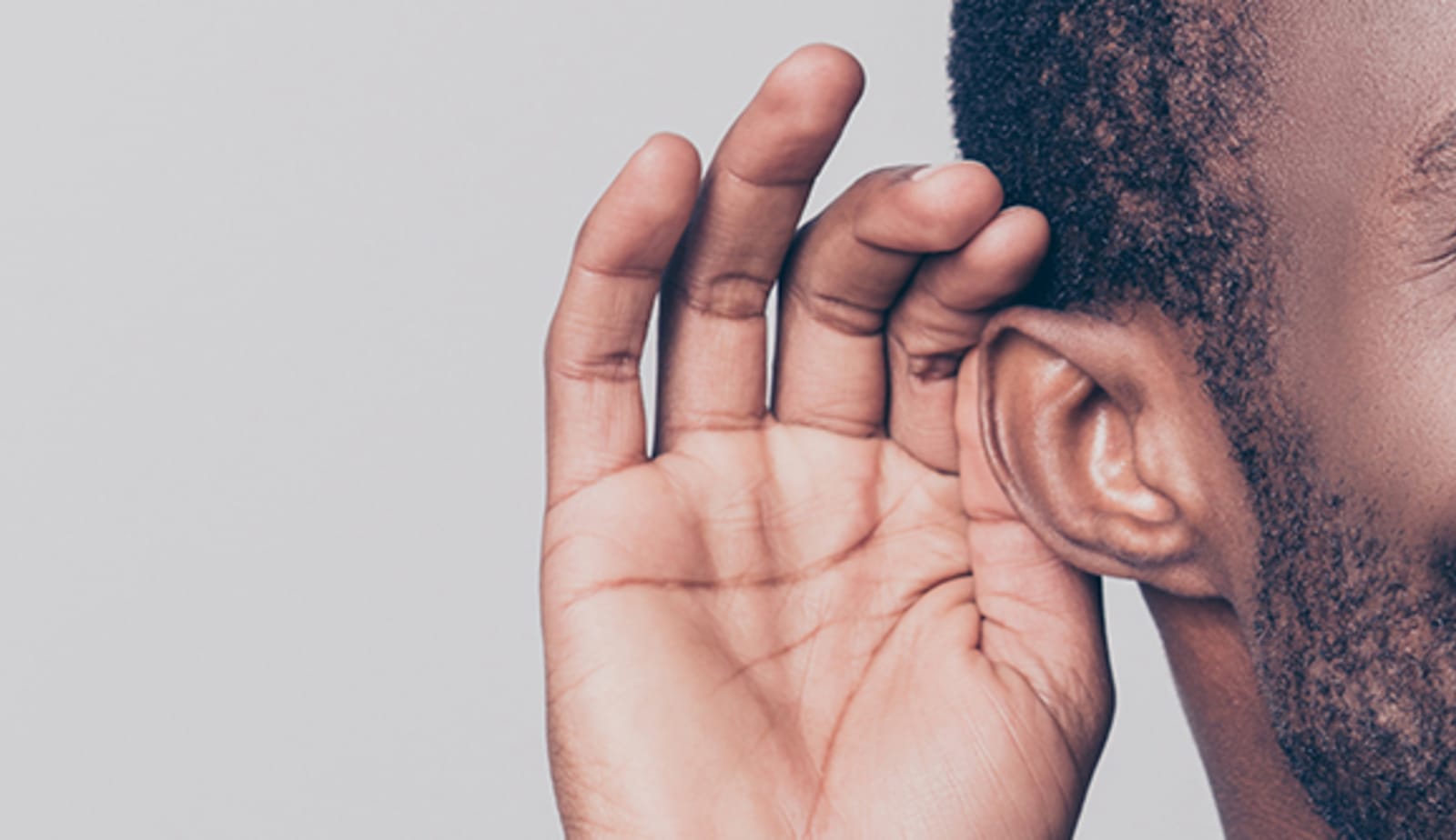 man with his hand to his ear to assist his hearing loss