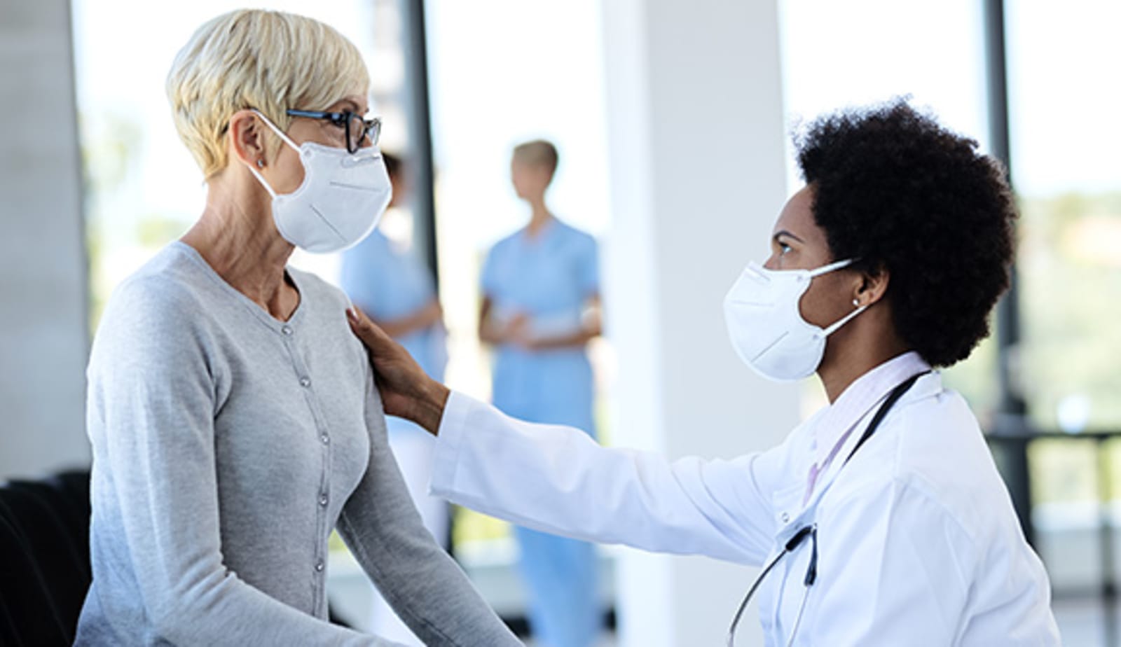 A physician and patient are sitting down looking at one another in a hospital lobby. 