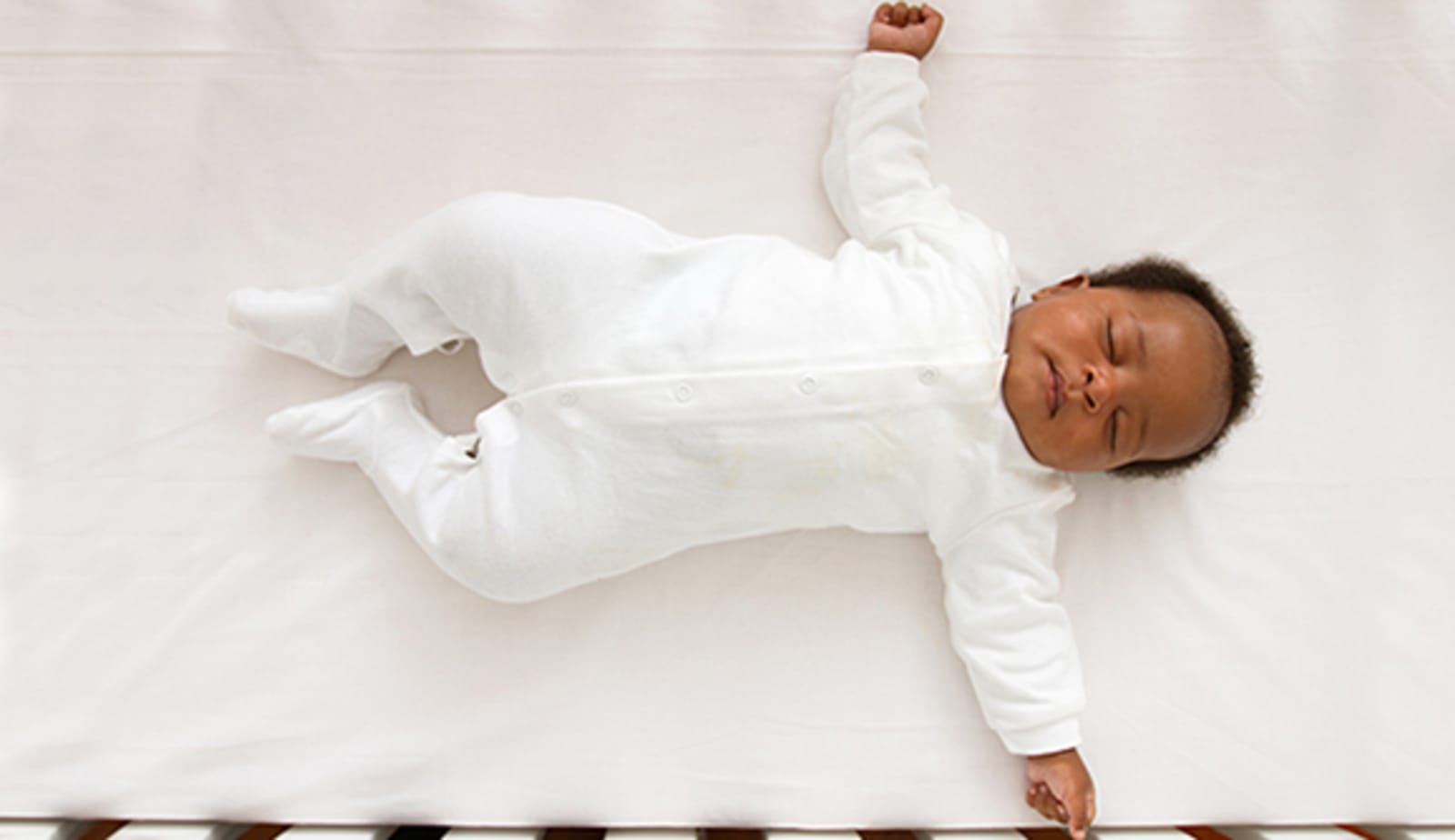 Baby sleeping flat on back on firm crib mattress