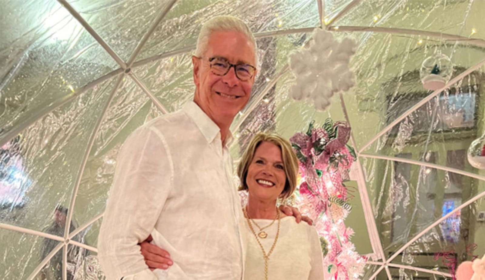 smiling couple posing in front of Christmas decorations