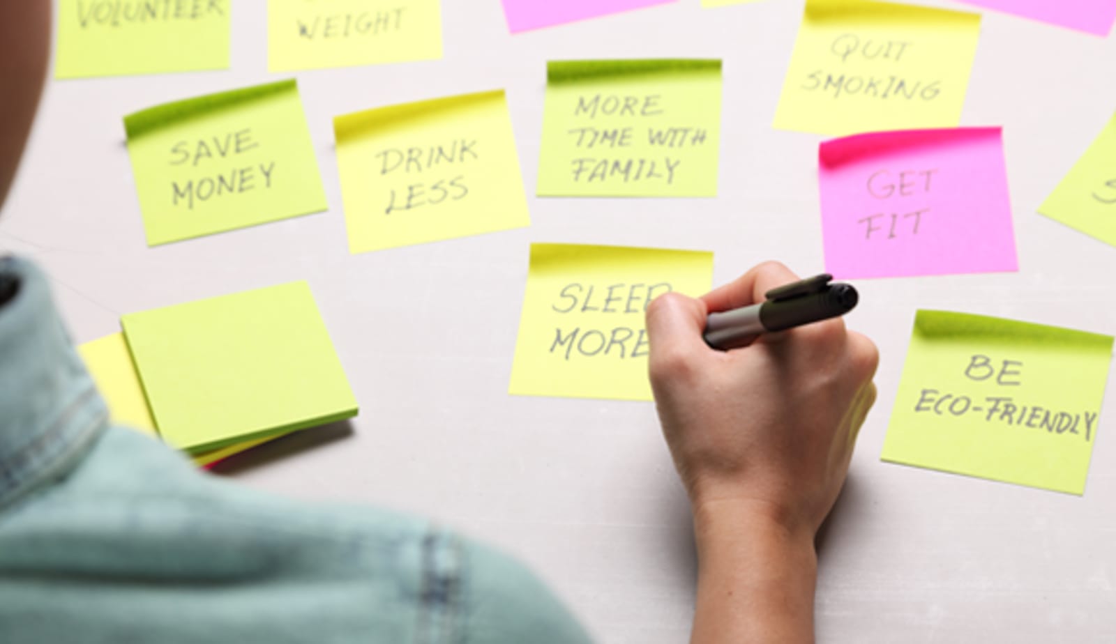 A person writing resolutions on sticky notes