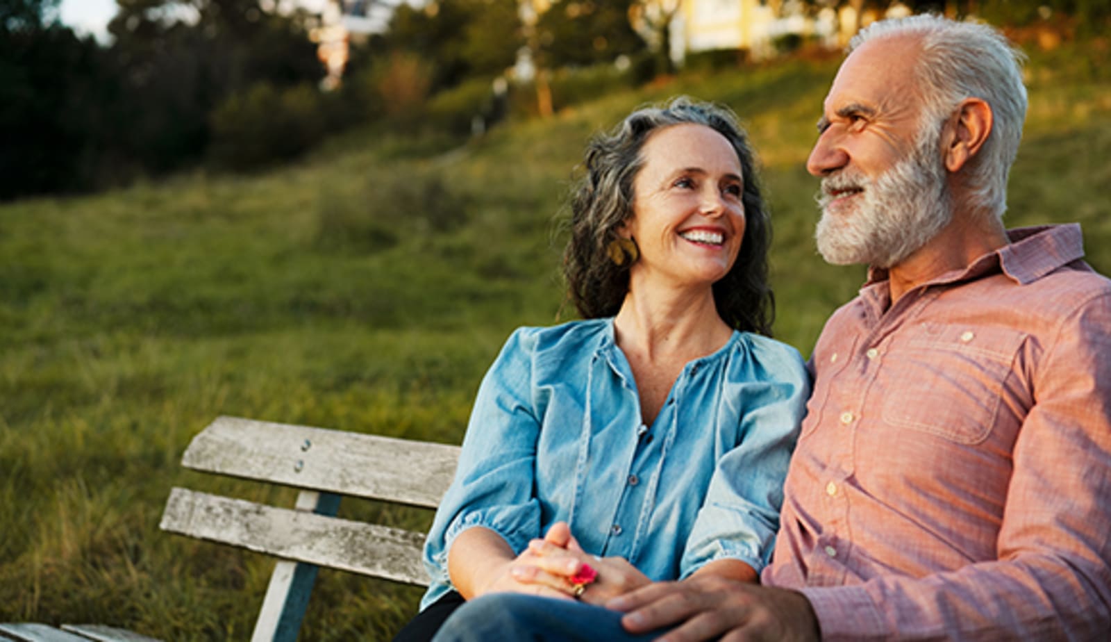 A senior couple happy and sitting on a park bench together