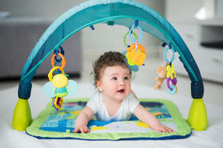 A baby plays on her tummy and looks at toys