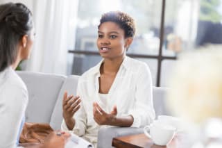 african american woman sitting on soft sofa in a well lit room being interviewed by a behavioral health therapist for insomnia sleep issues