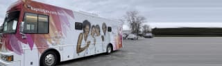 picture of a large pink and white bus with pictures of smiling women on the side.