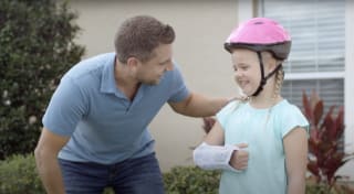 Little girl with arm cast and helmet smiling at her dad