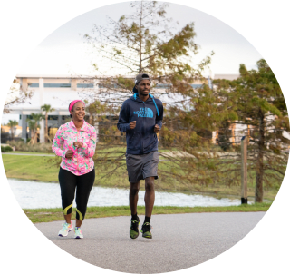 a man and woman jogging on the path at Baptist Clay Medical Campus.