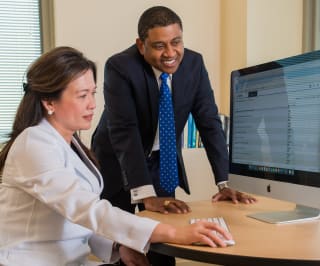 Dr. Groover and a physician look at a computer monitor together, both smiling.