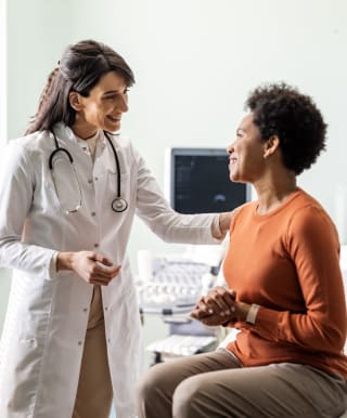 a female physician smiles at a female patient in a medical setting