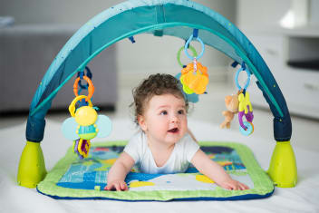 A baby plays on her tummy and looks at toys