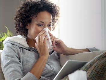 woman sneezing into tissue