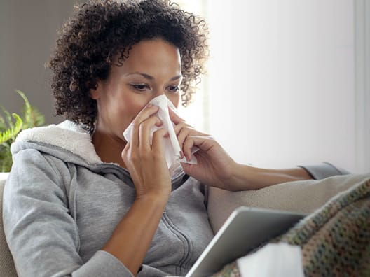 woman sneezing into tissue
