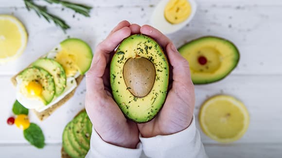 closeup of woman's hands holding avocado