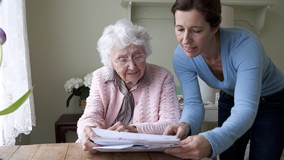 woman looking over paperwork with a senior woman at the dining room table