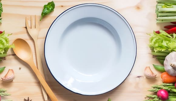 empty plate on a table with vegetables and wooden utensils