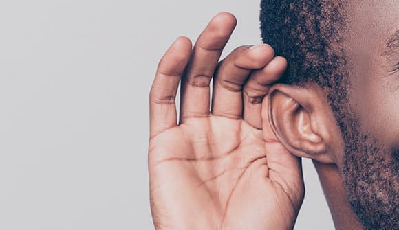 man with his hand to his ear to assist his hearing loss