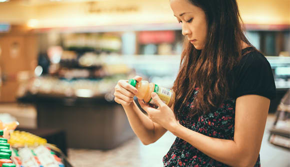 Asian woman studying food item in grocery store