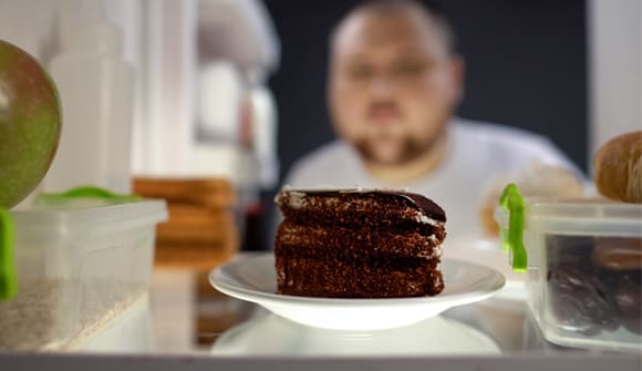 Man looking at chocolate cake in refrigerator
