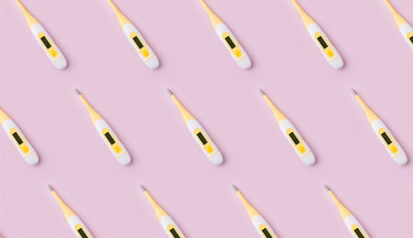 multiple yellow and white thermometers arranged on a pink background