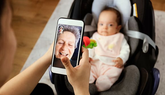 image of woman holding a phone toward her daughter to facetime with her mother