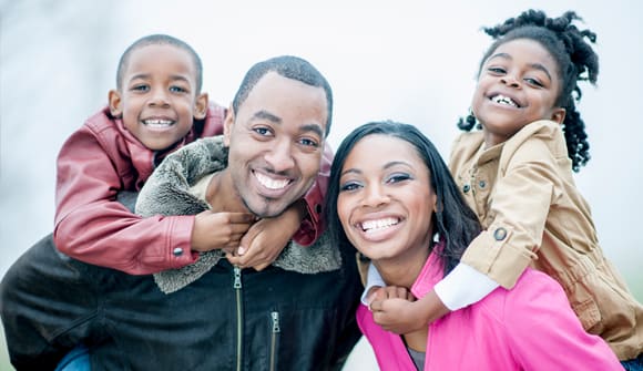 smiling family portrait of parents and two kids bundled up outside