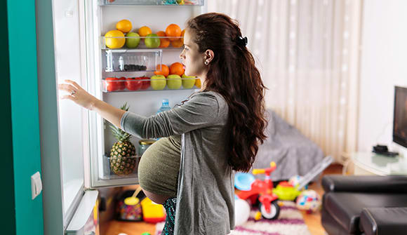 Pregnant woman looking for food in her fridge