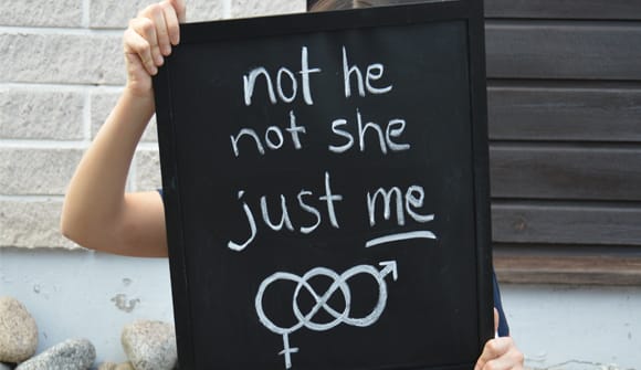 Person holding a sign that says "not he, not she, just me."