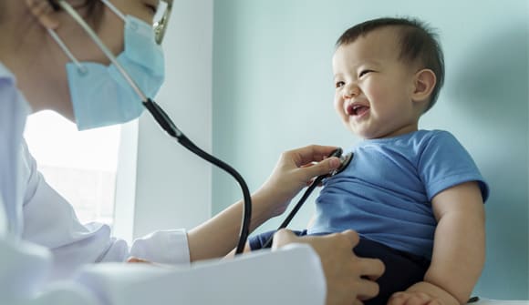 doctor checks the heart beat of a young laughing child