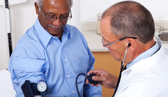 man getting his blood pressure taken by a doctor
