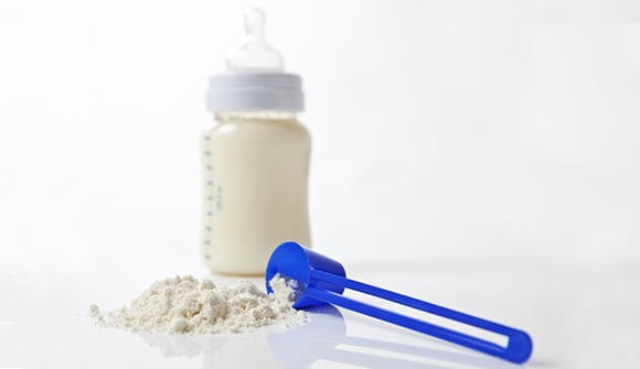 A close-up shot of baby milk formula with a plastic measuring spoon and bottle