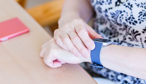 close up of a woman adjusting the blue smart watch on her wrist