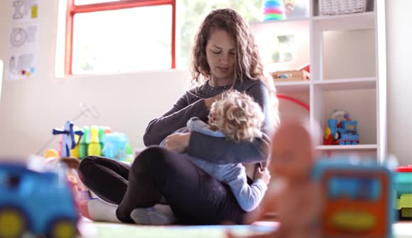 woman sitting in a playroom breastfeeding her young son