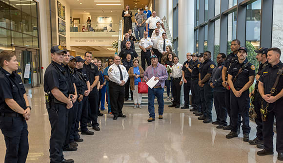 Image of a fire lieutenant walking through a tunnel of first responders as he descends a staircase into a lobby.