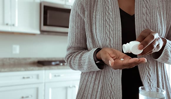 woman measuring out a pill in her kitchen