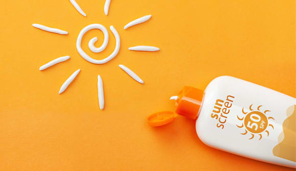 sunscreen bottle and sun drawn with sunscreen to help prevent skin cancer