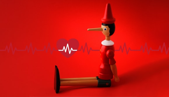pinocchio doll sitting in front of a heart and heart rhythm, illustrating fibs about afib