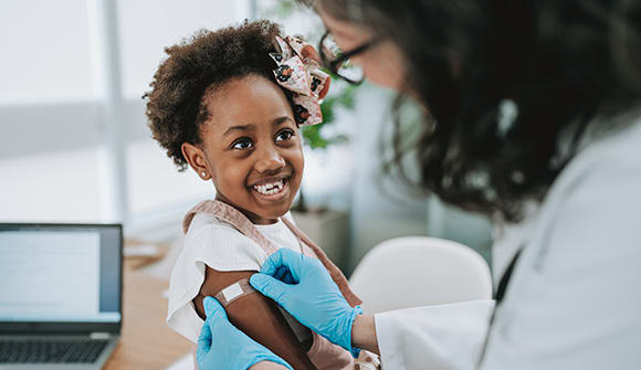 Doctor placing band-aid on child after receiving a vaccine