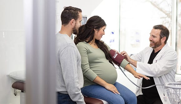 woman with high-risk pregnancy has her blood pressure checked by a high risk obgyn or maternal fetal medicine doctor